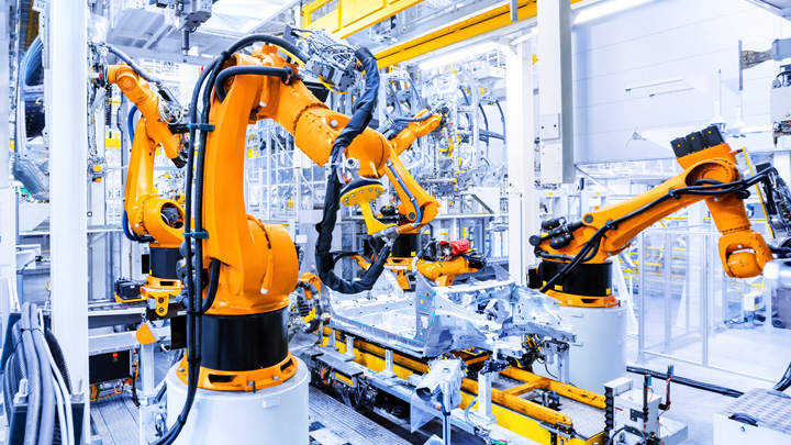 Braccia robotiche lavorano lungo una catena di montaggio automotive