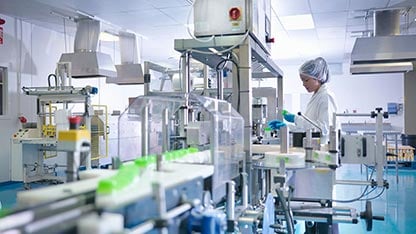 Operaio che ispeziona i prodotti sulla linea di produzione in una fabbrica farmaceutica