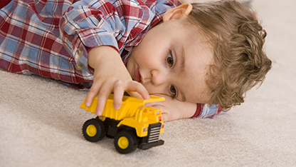 ragazzino che gioca con il camion giocattolo giallo